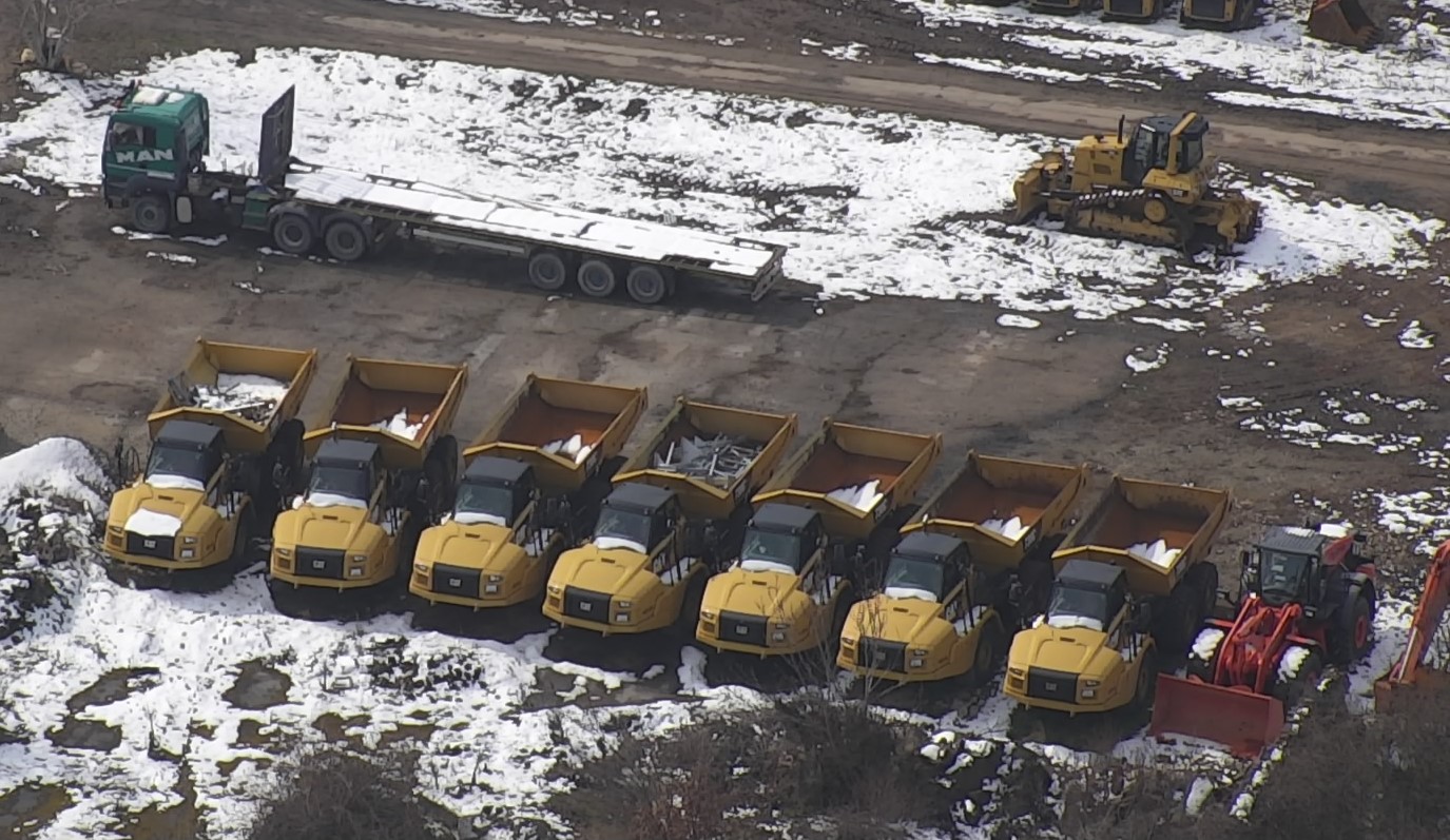 A row of yellow construction trucks in the snow in Bulgaria