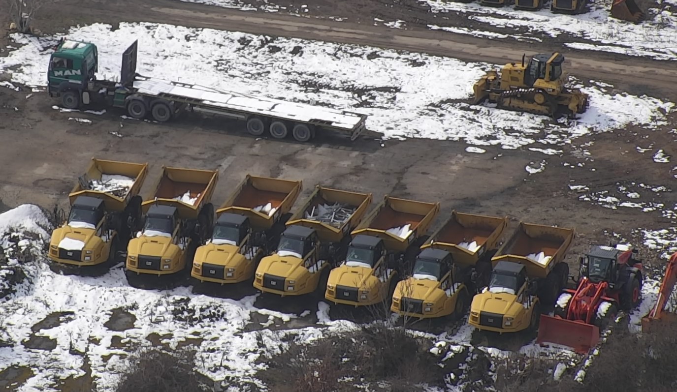 A row of yellow construction trucks in the snow in Bulgaria