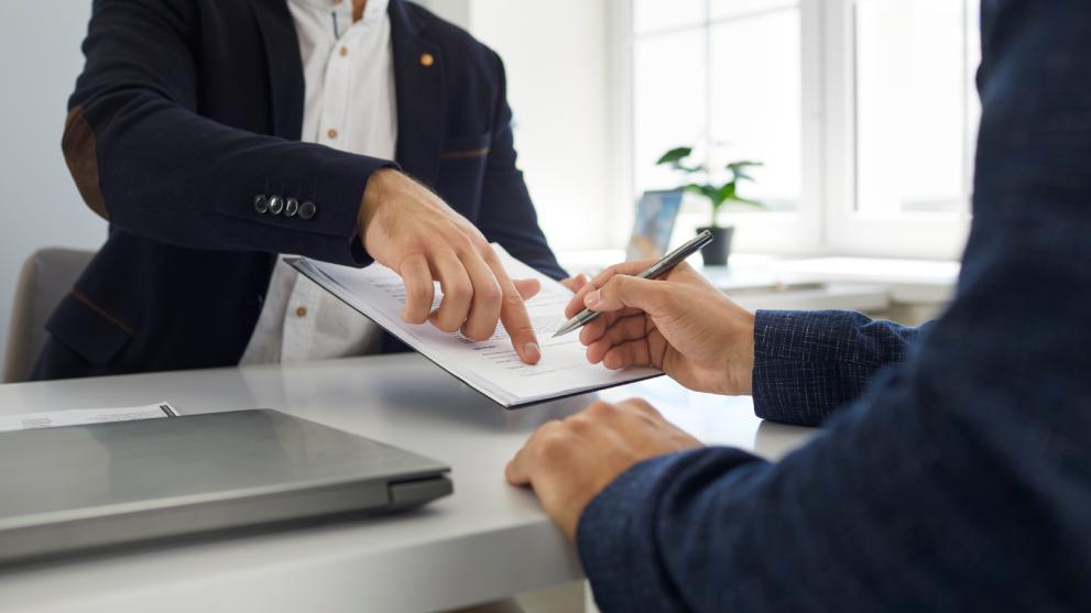 someone showing someone else where to sign