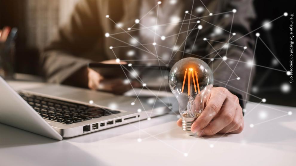 innovation, lightbulb on a desk next to a laptop
