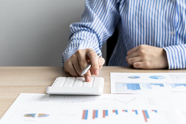 paper on desk with someone using a calculator